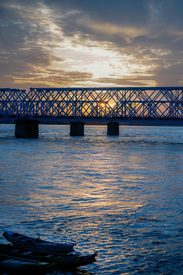 A serene view of the iron bridge over Krishna River during sunrise in Vijayawada, India.
